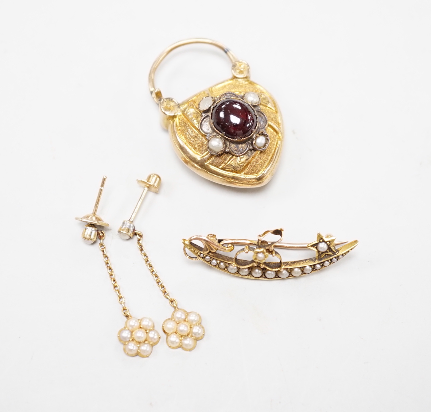 A Victorian yellow metal, garnet and seed pearl set heart shaped locket pendant, 36mm, a pair of Edwardian 15ct and seed pearl cluster set drop earrings and a yellow metal set seed pearl brooch.